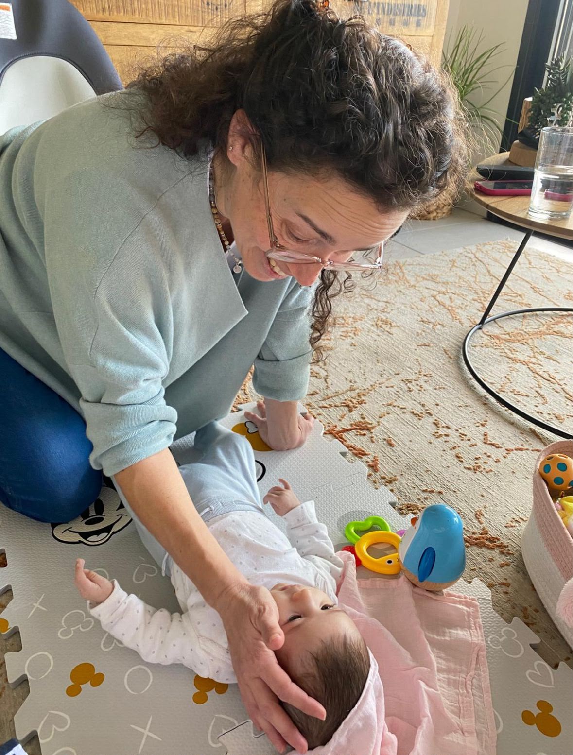 רוני משחקת עם תינוקת על השטיח